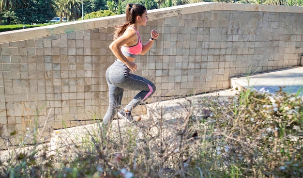 Jeune femme courant dans les escaliers avec une expression de motivation faisant de l'entraînement cardio dans le parc Concept de soins de santé