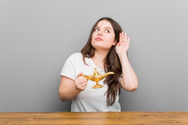 Jeune femme courbée de taille plus tenant une lampe magique essayant d'écouter un commérage.