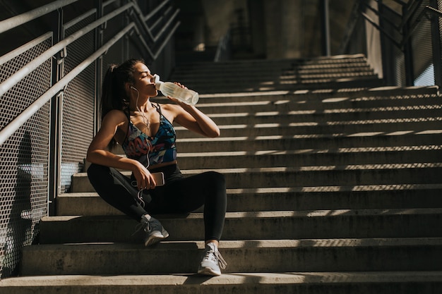 Jeune femme coureur se reposant dans les escaliers