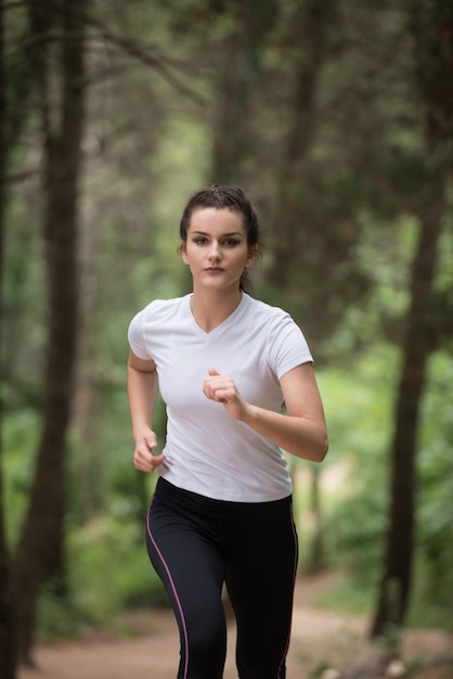 Jeune femme en cours d'exécution dans la forêt boisée de formation et d'exercice pour Trail Run Marathon Endurance Fitness Mode de vie sain Concept