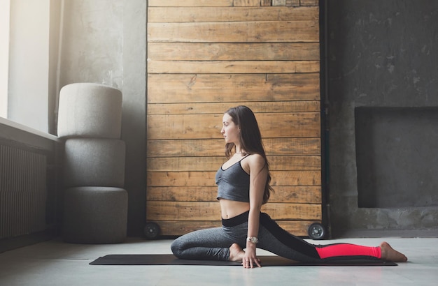 Jeune femme en cours de yoga qui s'étend de la tête aux genoux. Mode de vie sain dans un club de fitness. Élongation