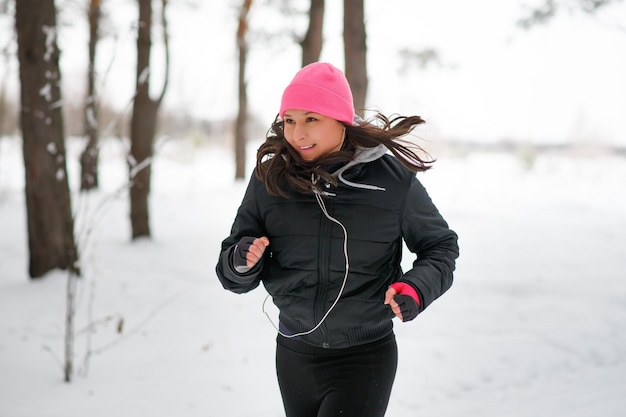 Une jeune femme court avec une forêt d'hiver