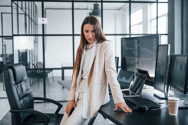 Jeune femme courtier en bourse est à l'intérieur dans le bureau