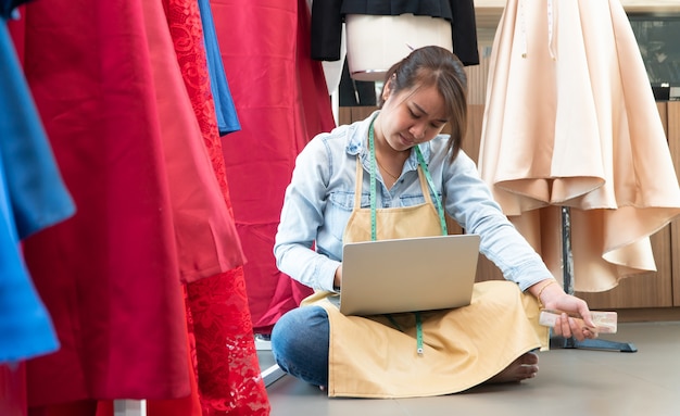 Jeune femme couturière à l'aide d'un ordinateur portable