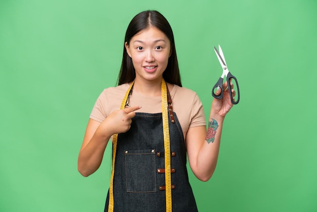 Jeune femme couturière asiatique sur fond isolé avec une expression faciale surprise