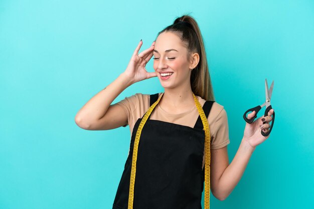 Jeune femme couturière caucasienne isolée sur fond bleu souriant beaucoup