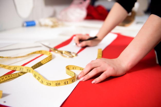 Jeune femme couturière coud des vêtements sur machine à coudre.