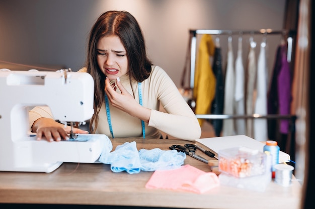 Jeune femme couturière coud des vêtements sur machine à coudre