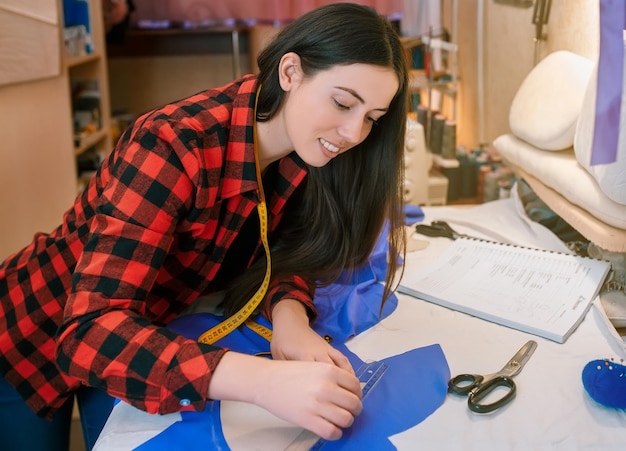 jeune femme couturière faisant un motif sur le tissu avec de la craie de tailleur