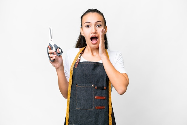 Jeune femme couturière sur fond blanc isolé avec une expression faciale surprise et choquée