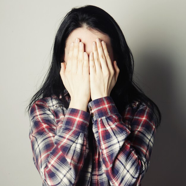 Jeune femme couvrant ses yeux avec ses mains.