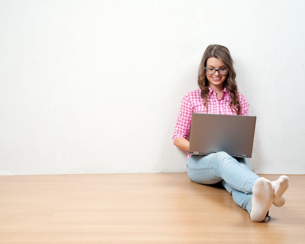 Jeune femme créative, assis dans le sol avec un ordinateur portable. Blogueur occasionnel femme