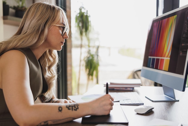 Jeune femme créative travaillant sur ordinateur depuis son bureau à domicile.