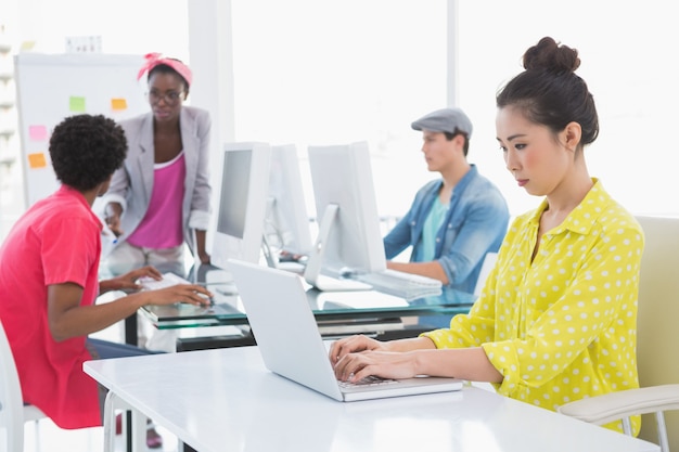 Jeune femme créative utilisant l&#39;ordinateur portable au bureau