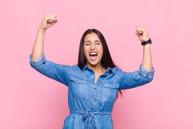 Jeune femme criant triomphalement, ressemblant à un gagnant excité, heureux et surpris, célébrant