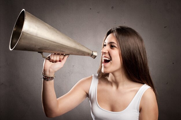 Jeune femme criant avec un vieux mégaphone