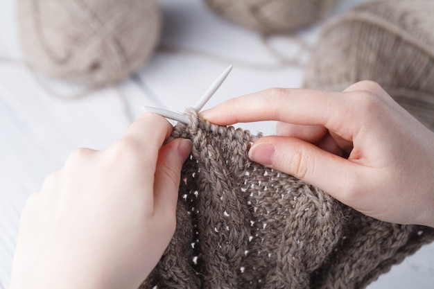 Jeune femme crochète une couverture chaude avec de la laine beige