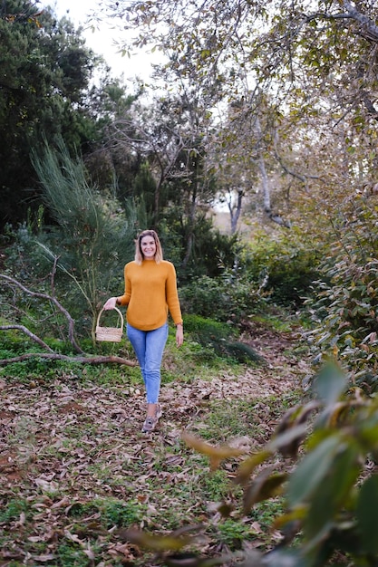 Jeune femme cueillant des châtaignes en automne au coucher du soleil avec des feuilles au sol