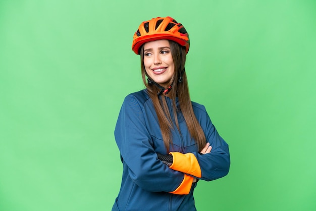 Jeune femme cycliste sur fond isolé chroma key avec les bras croisés et heureux