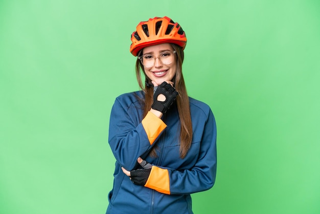 Jeune femme cycliste sur fond isolé chroma key avec des lunettes et souriant