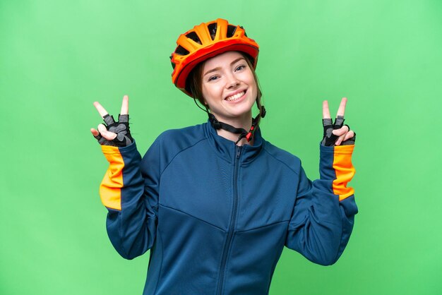 Jeune femme cycliste sur fond isolé chroma key montrant le signe de la victoire avec les deux mains