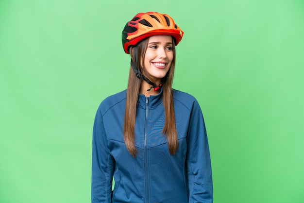 Jeune femme cycliste sur fond isolé chroma key à la recherche de côté