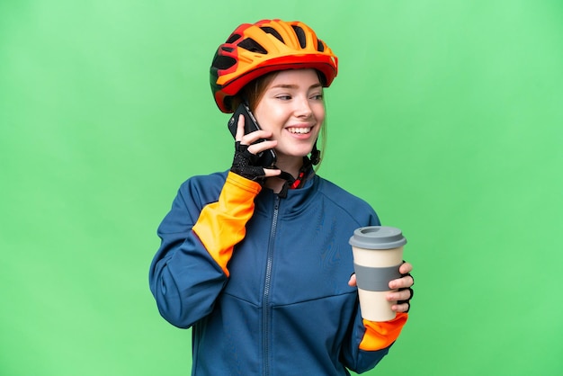 Jeune femme cycliste sur fond isolé chroma key tenant du café à emporter et un mobile