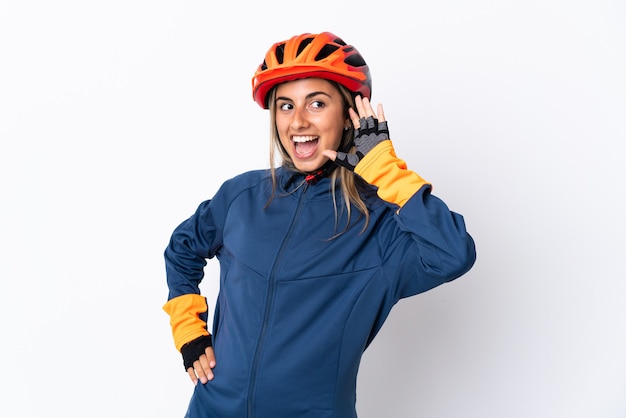 Jeune femme cycliste hispanique isolée sur blanc en écoutant quelque chose en mettant la main sur l'oreille