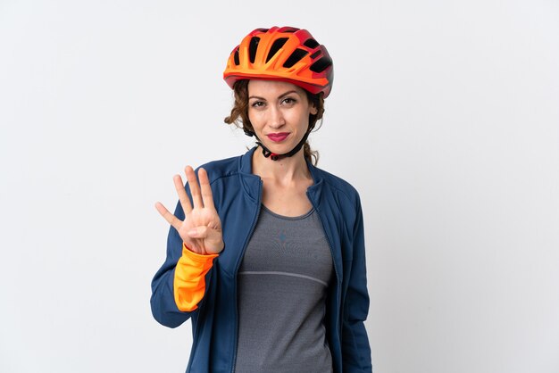 Jeune femme cycliste isolée sur un mur blanc heureux et comptant quatre avec les doigts