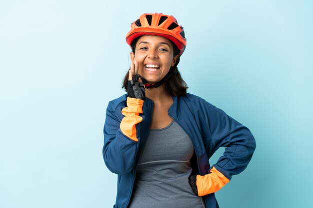 Jeune femme cycliste isolée sur mur bleu en criant avec la bouche grande ouverte