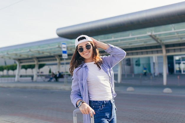 Jeune femme dans un bonnet blanc avec une valise