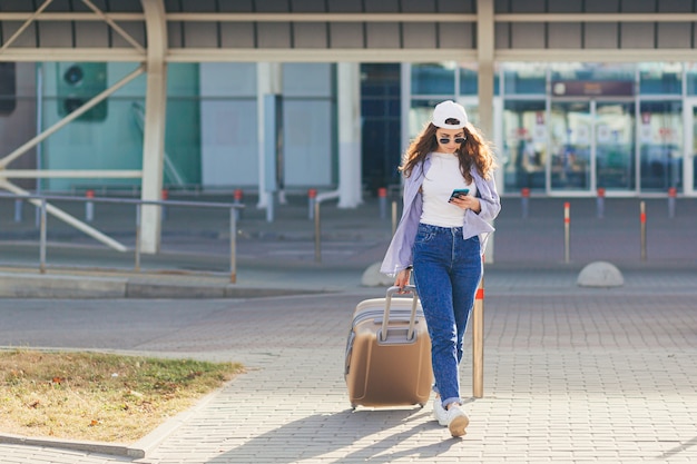 Jeune femme dans un bonnet blanc avec une valise