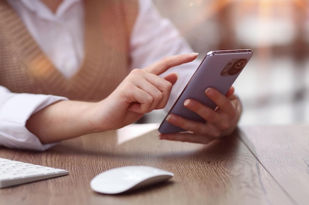 une jeune femme dans un bureau moderne navigant sur un smartphone