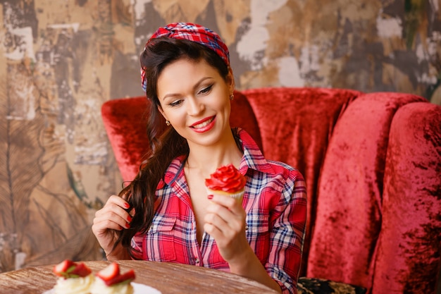 Une jeune femme dans un café assis à une table avec des gâteaux, pin up