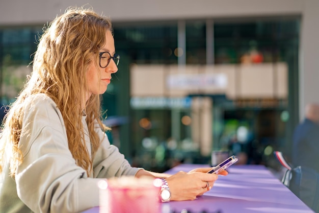 Jeune femme dans un café lisant un SMS depuis son téléphone portable