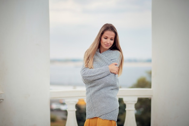 Jeune femme dans un cardigan gris sur une terrasse