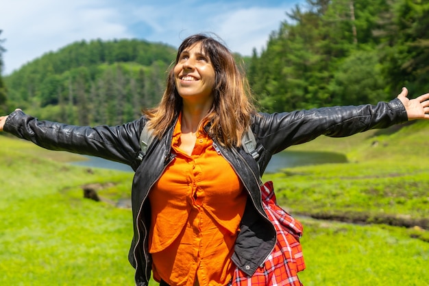 Jeune femme dans un champ avec un lac et une forêt de pins