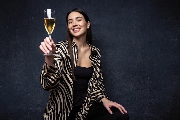 Une jeune femme dans une chemise et un pantalon élégants buvant du champagne