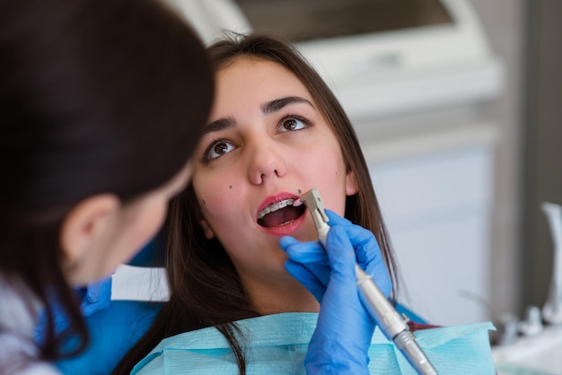 Une jeune femme dans une clinique dentaire avec un dentiste La femme avec des accolades sourit Le concept de dents saines