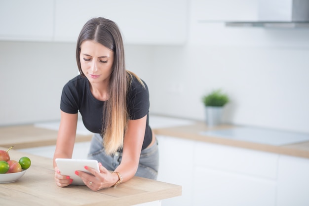 Jeune femme dans la cuisine à domicile avec tablette.