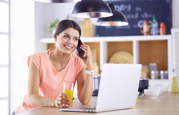 Jeune femme dans la cuisine avec un ordinateur portable à la recherche de recettes souriant Concept de blogueur alimentaire