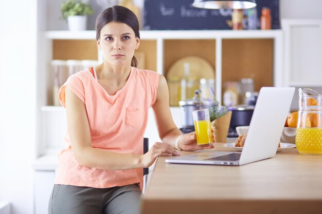 Jeune femme dans la cuisine avec un ordinateur portable à la recherche de recettes souriant Concept de blogueur alimentaire