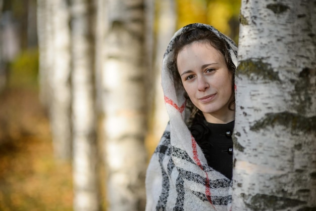 Une jeune femme dans un foulard dans un parc en automne