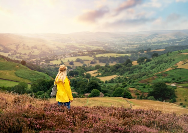 Une jeune femme dans un imperméable jaune vif marchant dans les champs du Peak District