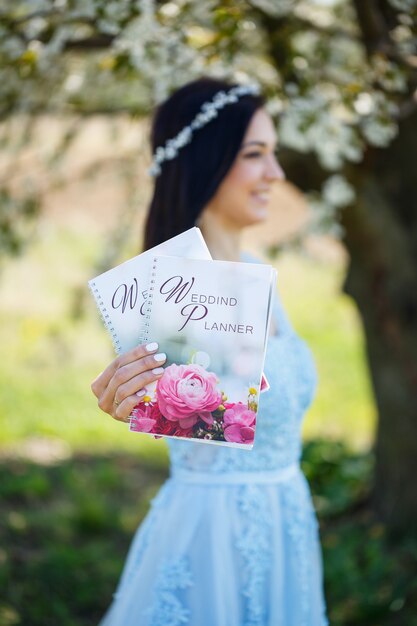 La jeune femme dans une longue robe bleue tient un planeur de mariage dans ses mains