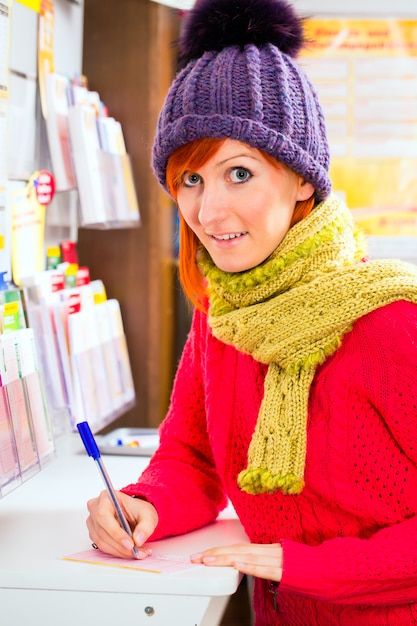 Jeune femme dans un magasin de loto jouant un billet