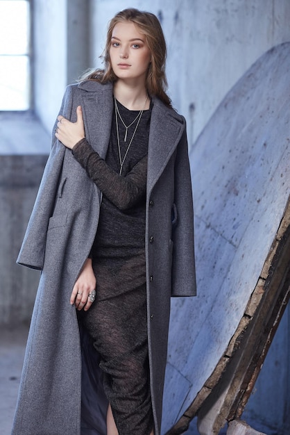 Jeune femme dans un manteau de printemps gris et une robe noire.