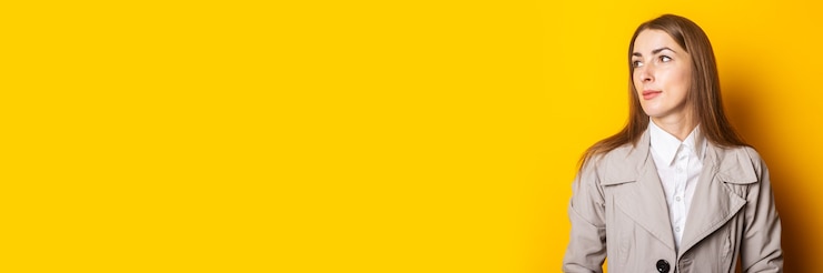 Photo jeune femme dans un manteau regarde sur le côté sur un fond jaune