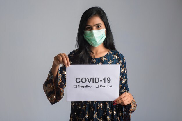 Une jeune femme dans un masque médical tenant une planche de l'épidémie de coronavirus, Covid-19