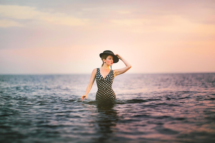 Photo une jeune femme dans la mer contre le ciel au coucher du soleil